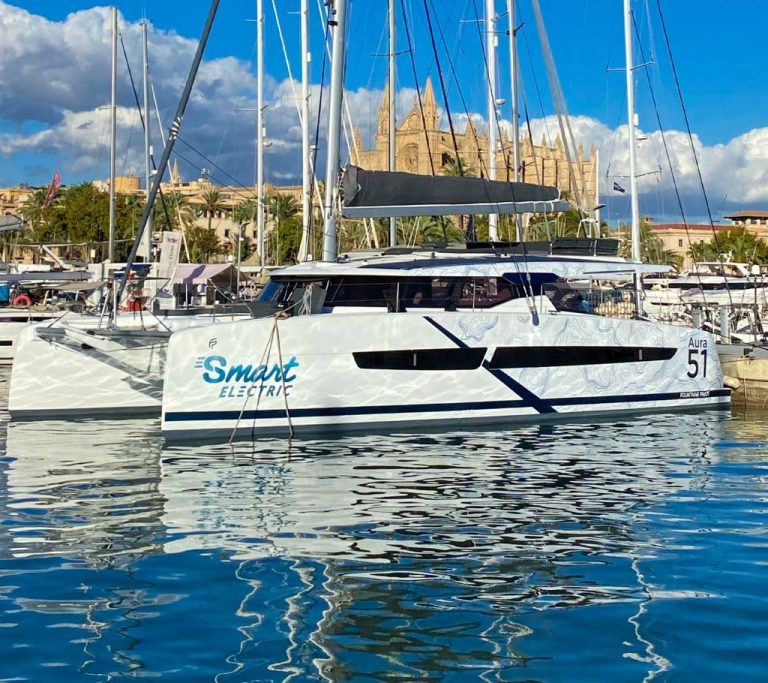 A white catamaran is moored in the water at PORT VELL for the Barcelona Boat Show 2023.