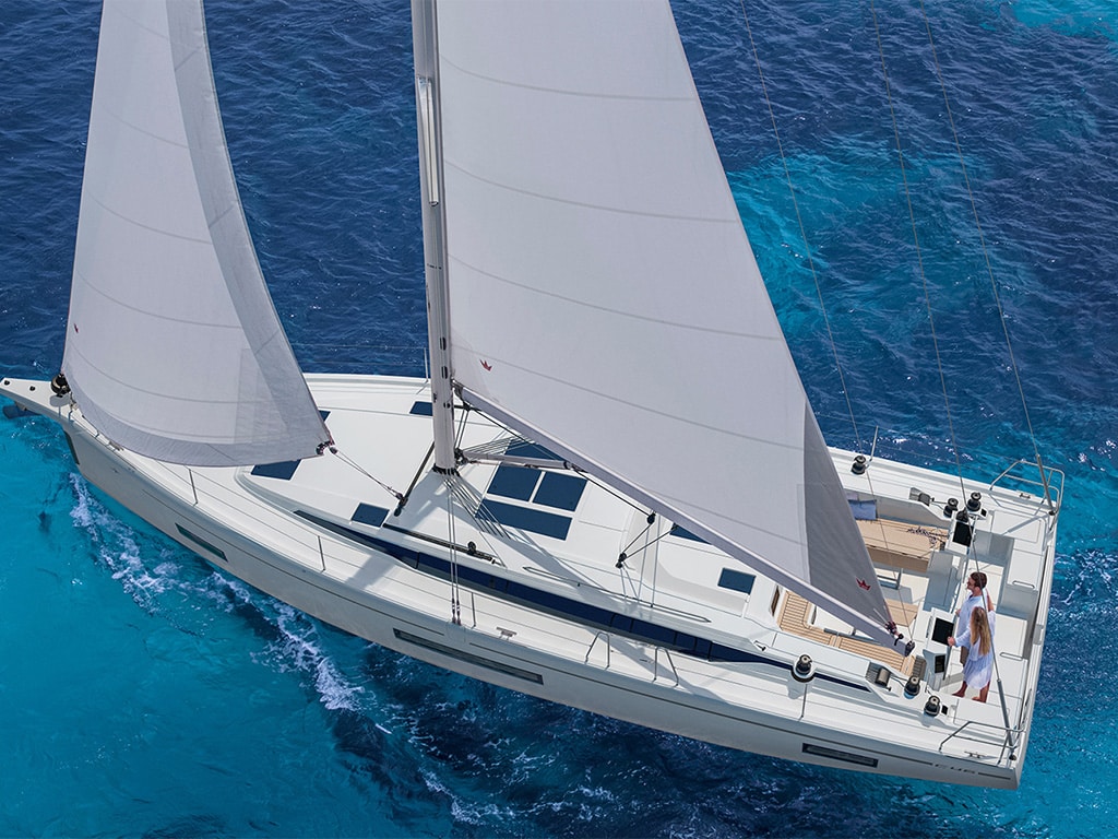 An aerial view shows a Bavaria C46 sailing yacht in the ocean. The yacht charter offers an impressive and aesthetic experience of seafaring and adventure. The wide perspective emphasizes the elegance and power of the ship, at the same time it also represents the freedom of being far away from the shore, surrounded by the endless beauty of the ocean.