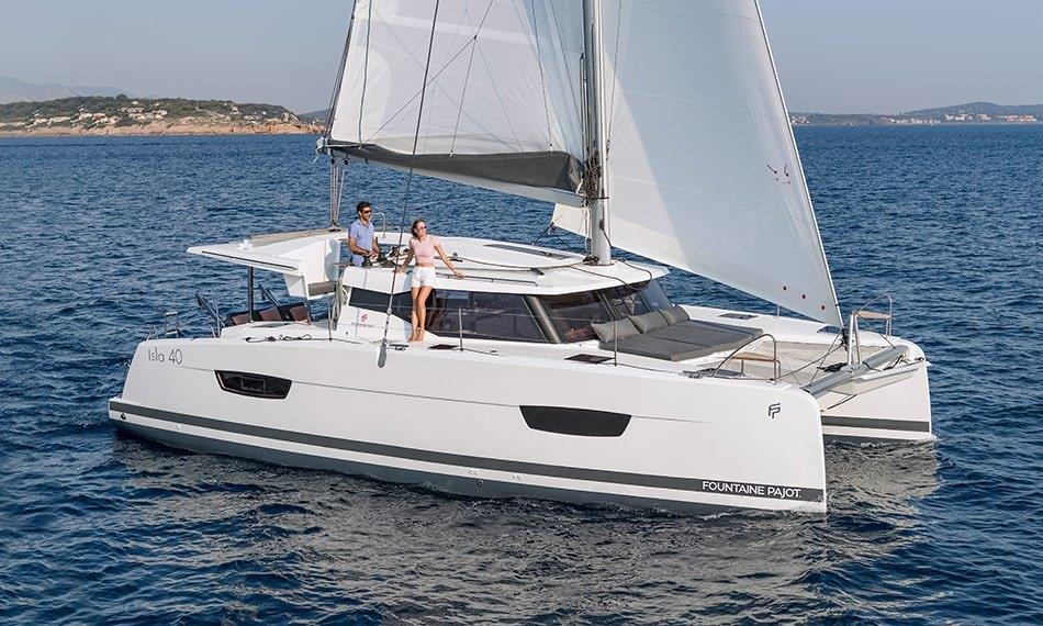 A white Fountaine Pajot Isla 40 catamaran with two people on board.
